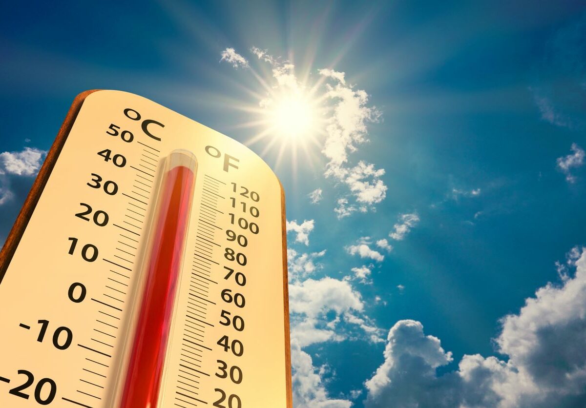 Low angle view Thermometer on blue sky with sun shining.