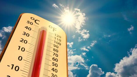 Low angle view Thermometer on blue sky with sun shining.