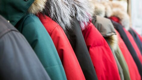 An assortment of winter and down jackets on hangers in a row.